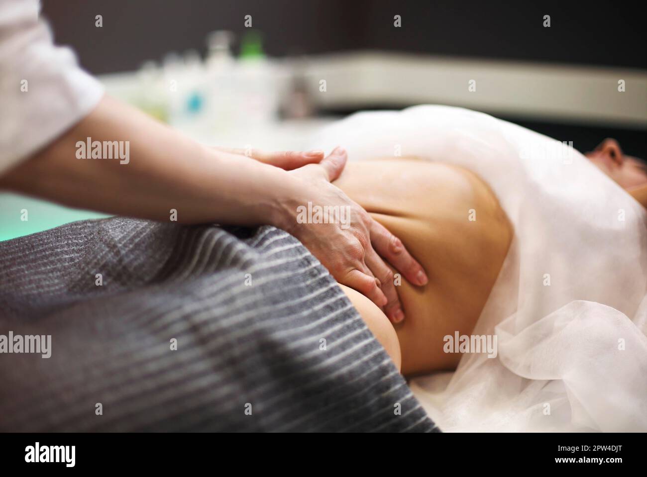 Teilansicht des Masseurs, der auf dem Massagetisch eine Magenmassage für die Frau macht Stockfoto
