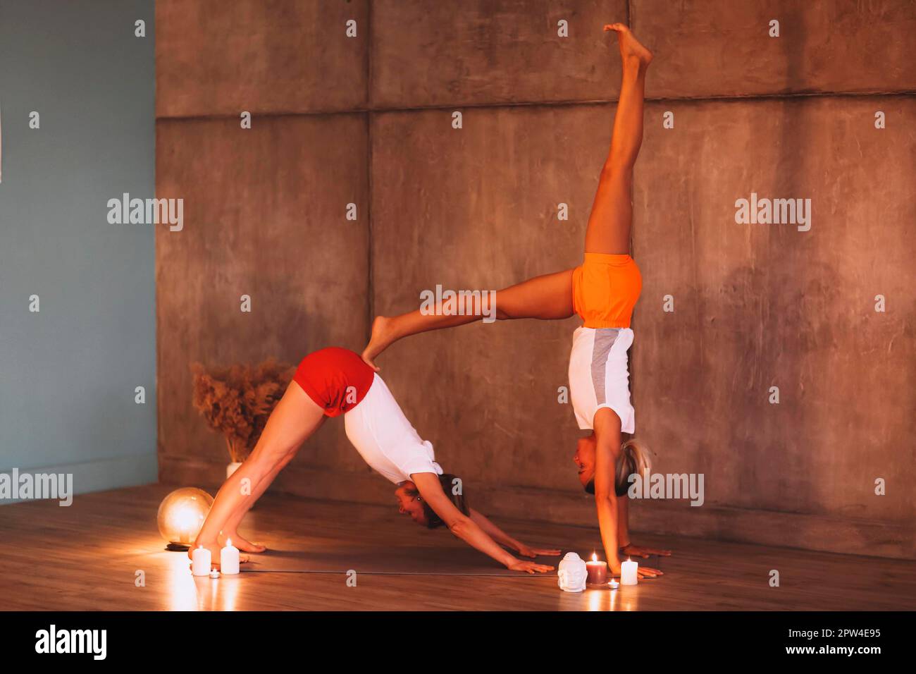 Zwei junge schlanke Frauen in bunten Sportbekleidung, die Yoga zum Entspannen machen, attraktive Frauen, die Stretching-Übungen machen. Sport Indoor und gesund Stockfoto