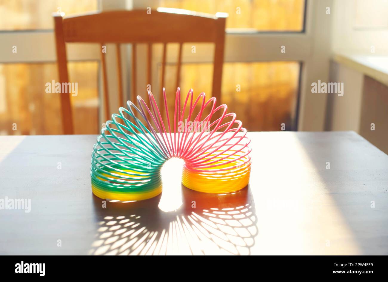 Anti-Stress-Zauberring Frühling Regenbogen Sprungspielzeug auf Tisch in sonnigen Raum zu Hause, selektive Fokus. Stressabbau und Anti-Angst-Spielzeug Konzept Stockfoto