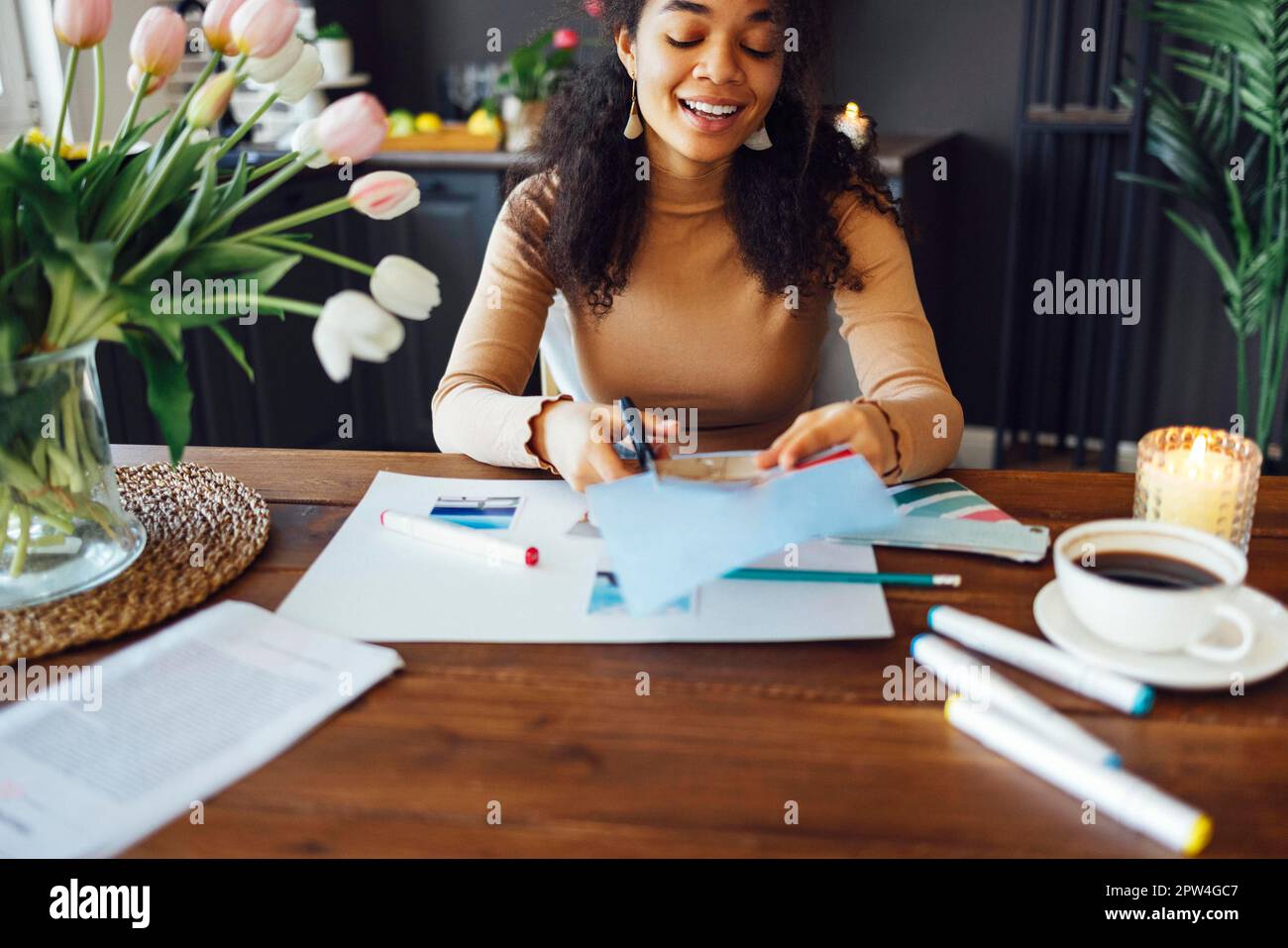 Junge Brünette afroamerikanische Frau, die ihre Feng Shui Wunschkarte mit einer Schere erstellt. Träume und Wünsche Stockfoto