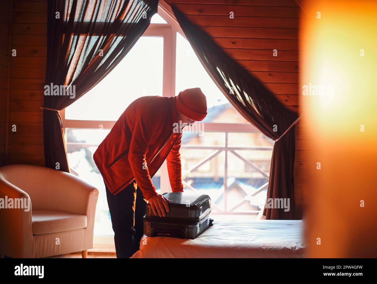 Stilvoller Hipster-Reisender mit rotem Hut im Holzhaus-Koffer, Winterreisekonzept, Platz für Text, gemütlicher Moment. Urlaub und Reisen Stockfoto