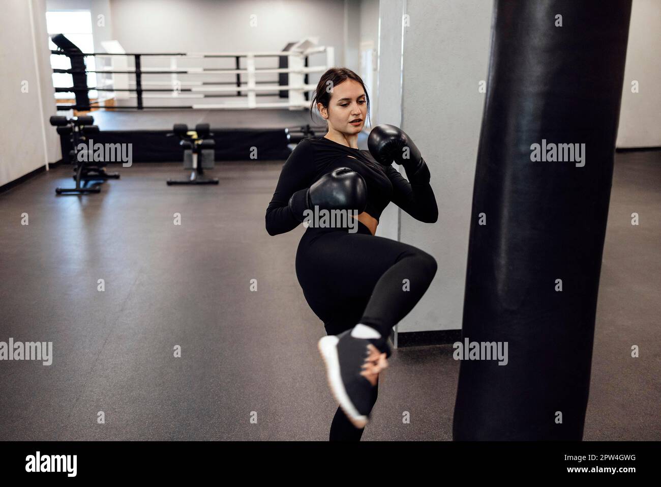 Eine starke latino-Boxerin springt in einen riesigen Boxsack im Fitness-Studio. Sportliches Mädchen trainiert Muay Thai Boxen für Bodybuilding und gesund Stockfoto