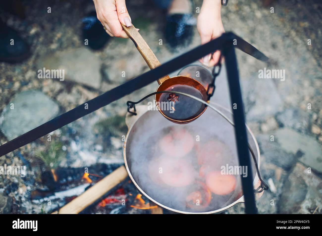 Von oben traditionellen Glühwein mit Scheiben von Orange Vorbereitung Im Topf über brennenden Baumstämmen im Winter auf dem Land Stockfoto