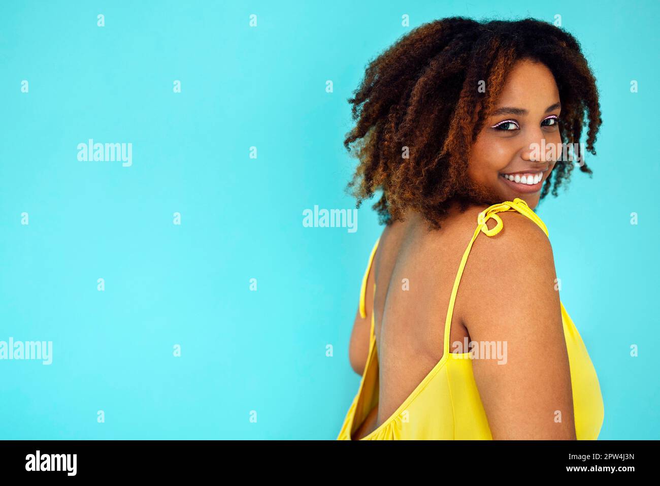 Schöne helle fröhliche afrikanische Frau in gelbem Kleid im blauen Studio-Hintergrund Stockfoto
