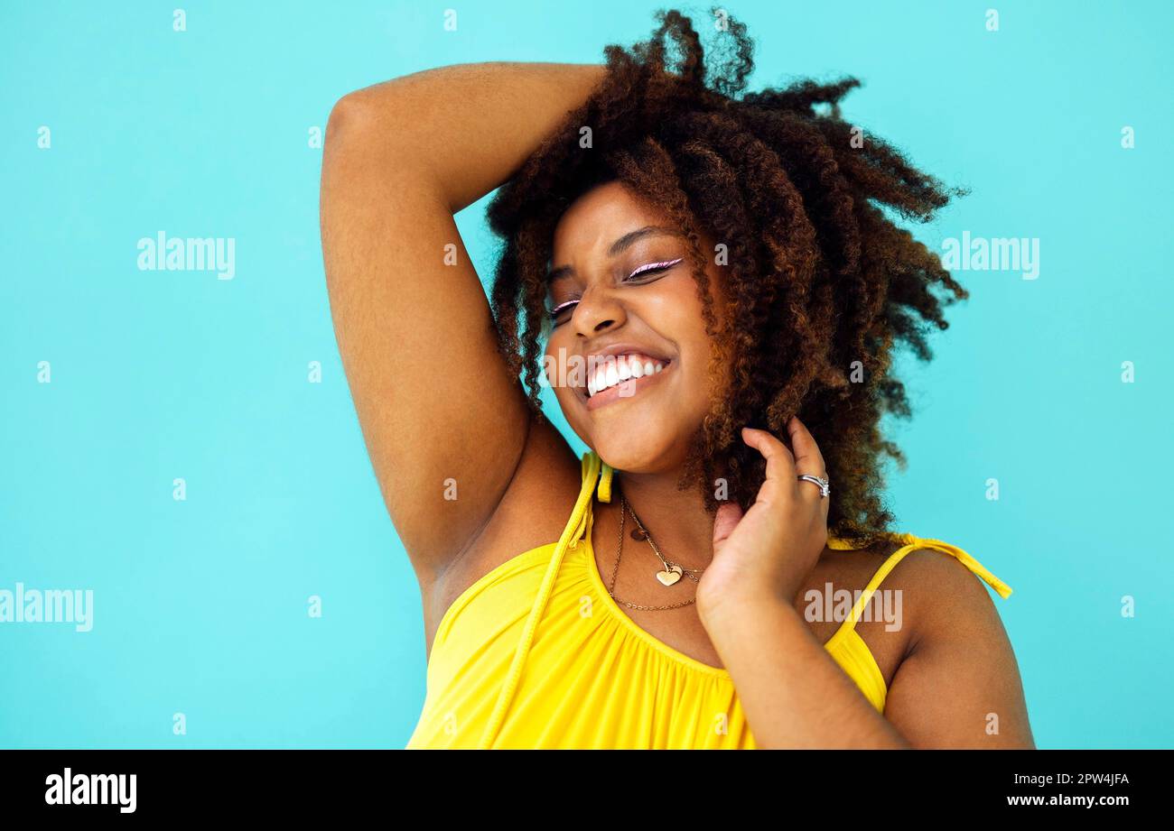 Schöne helle fröhliche afrikanische Frau in gelbem Kleid im blauen Studio-Hintergrund Stockfoto