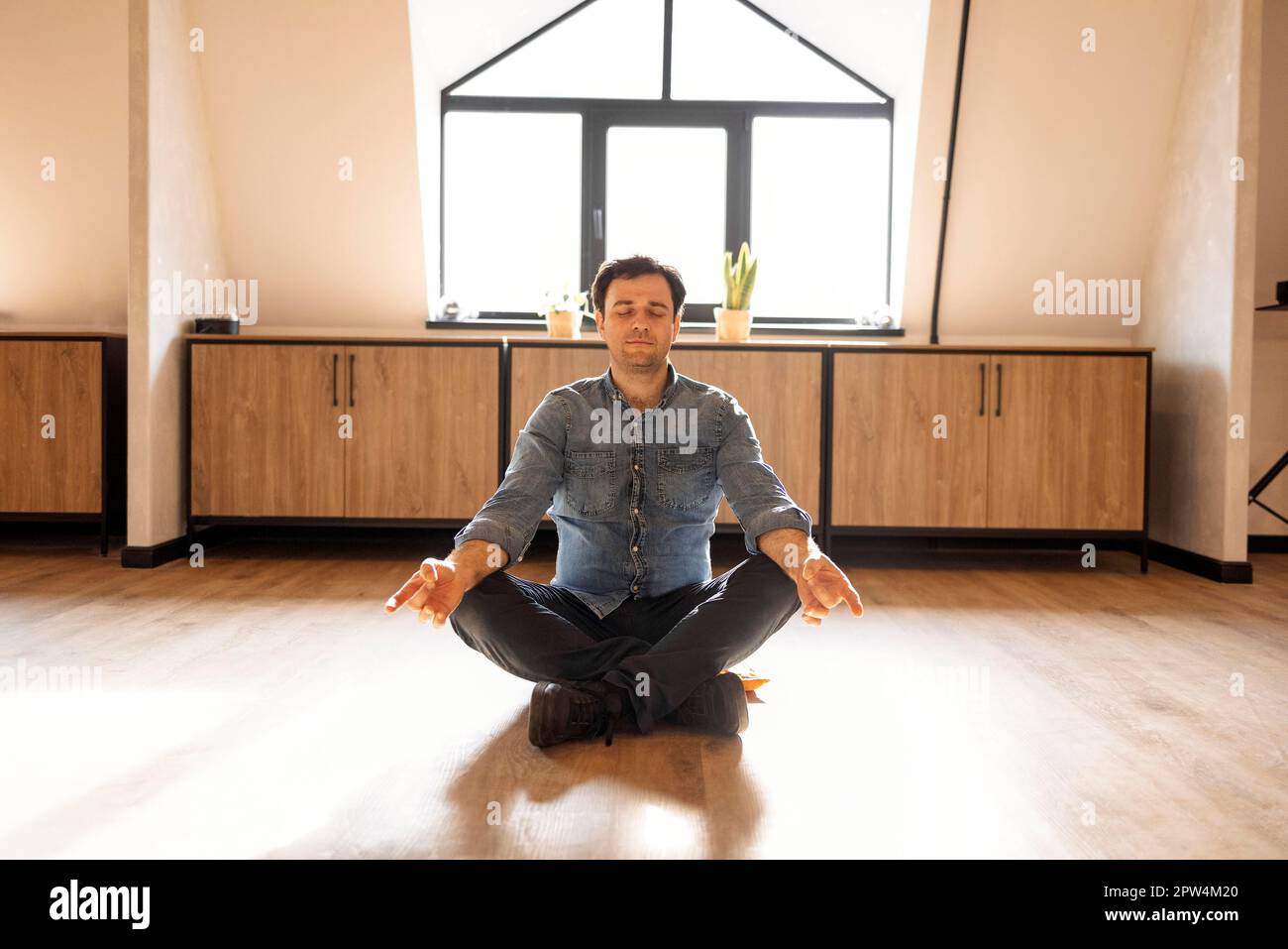 Gutaussehender hispanischer Mann trägt Jeans Casual Shirt sitzt auf dem Boden zu Hause entspannen, Meditation Geste mit den Fingern zu tun. Yoga-Konzept Stockfoto