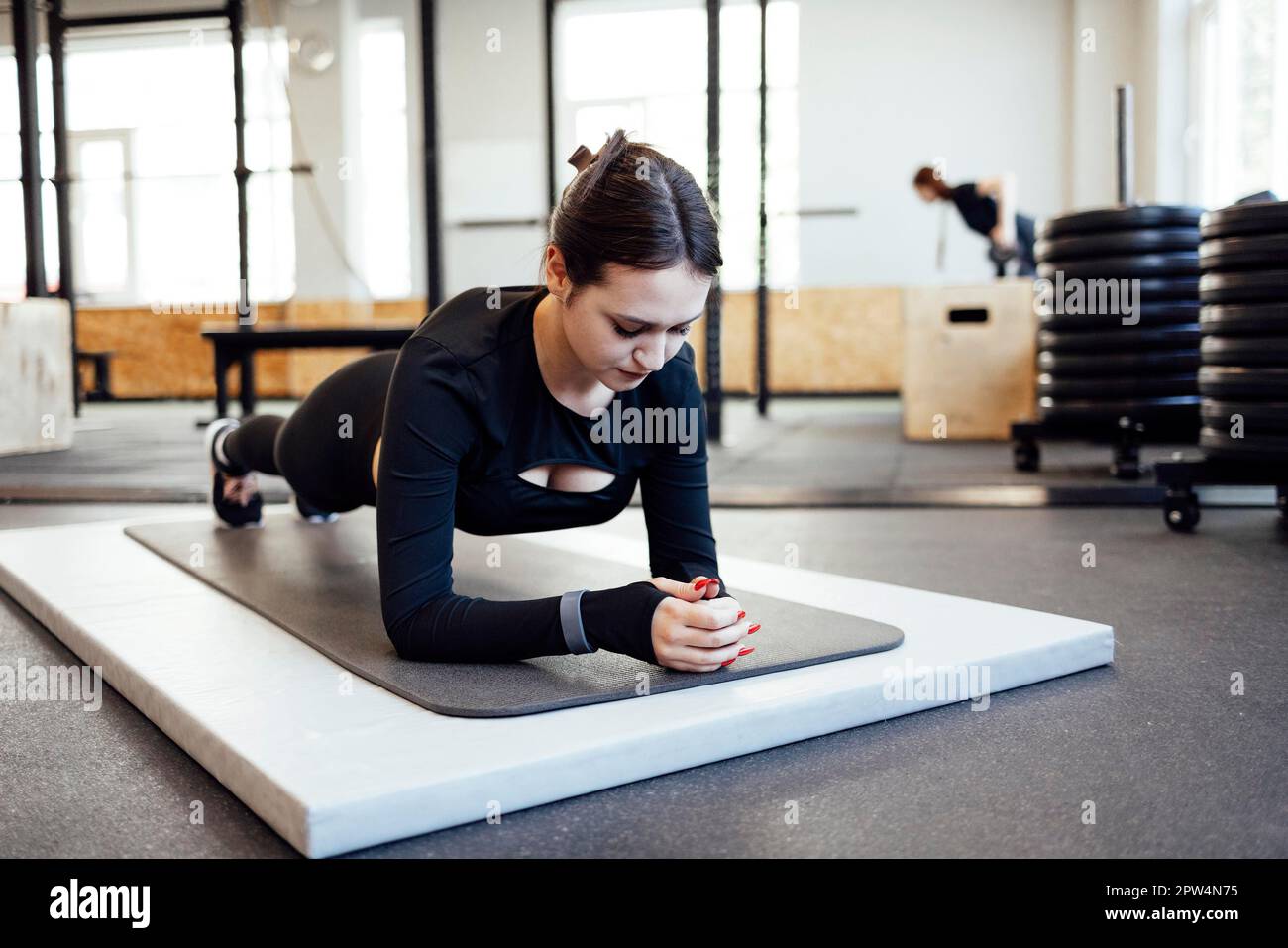 Junge schöne Frau, die sich vor dem Training im Fitness-Studio, Sport und Gesundheitskonzept dehnt und aufwärmt Stockfoto