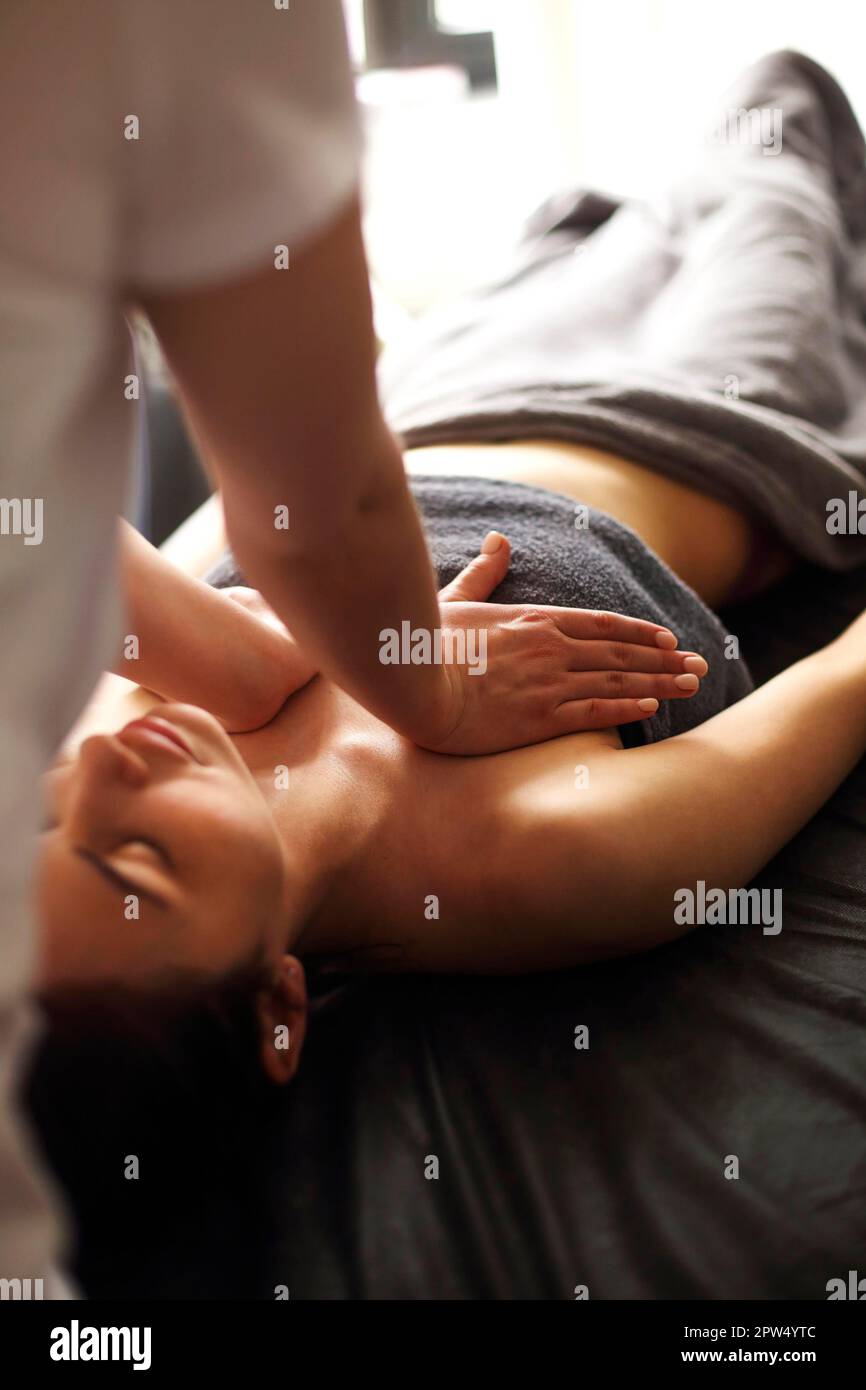Nicht erkennbarer Masseur massiert Brust der weiblichen Klientin liegend Tisch im Spa-Salon Stockfoto