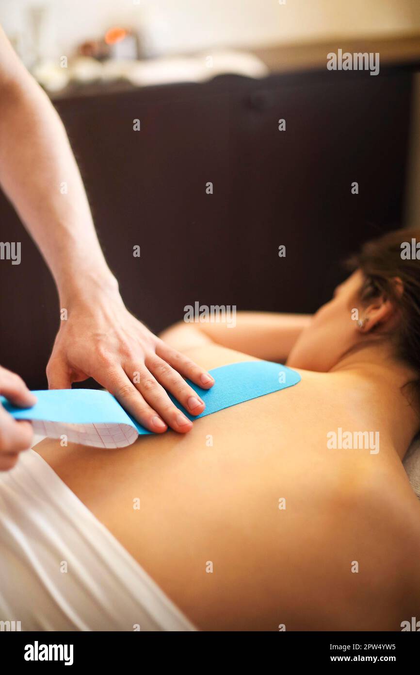 Crop Masseur Anwendung Kinesiologie Klebeband auf der Rückseite der anonymen Frau Während einer Massage im Spa-Salon Stockfoto