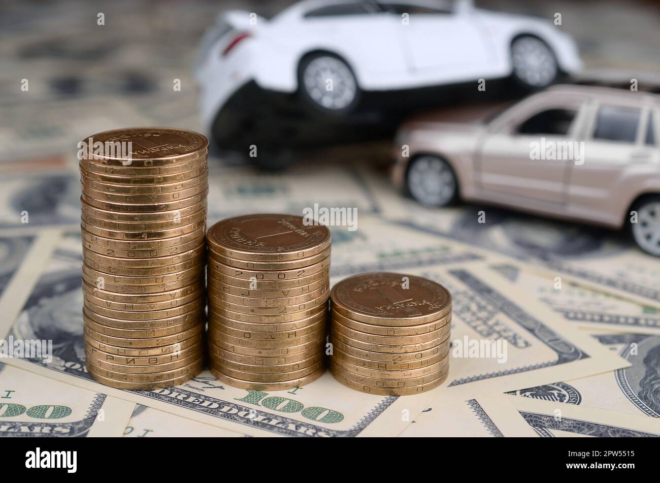 Spielzeug Auto Unfall auf einem Hintergrund von 100 Dollar, Rechnungen und Stapel von Goldmünzen. Auto Versicherung Konzept Stockfoto