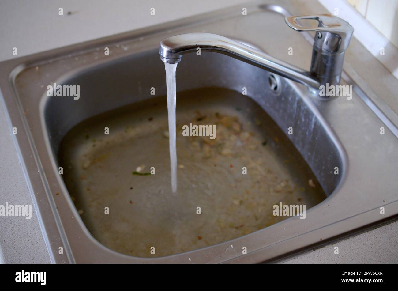 Edelstahl Waschbecken Stecker Bohrung close up voller Wasser und Partikel von Essen. Überquellenden Spüle, verstopften Abfluß. Probleme mit der Wasserversorgung Stockfoto