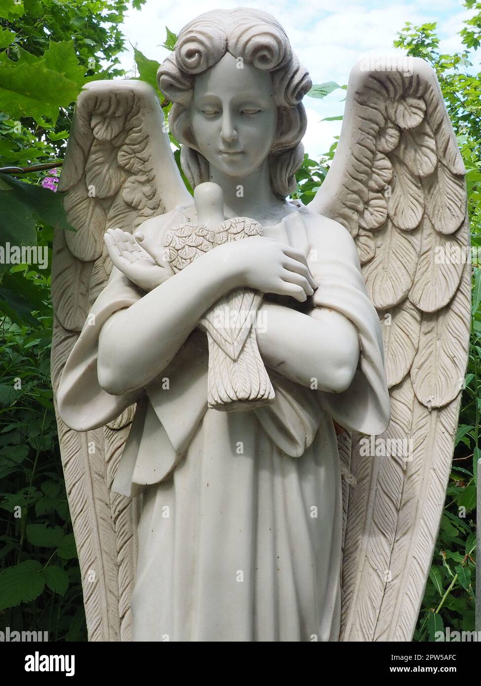 Ein Engel mit einer Taube. Skulptur auf dem Friedhof. Die Gestalt eines Engels mit Flügeln, der einen Vogel in den Armen hält. Klagen für den Verstorbenen. Grabstein Stockfoto