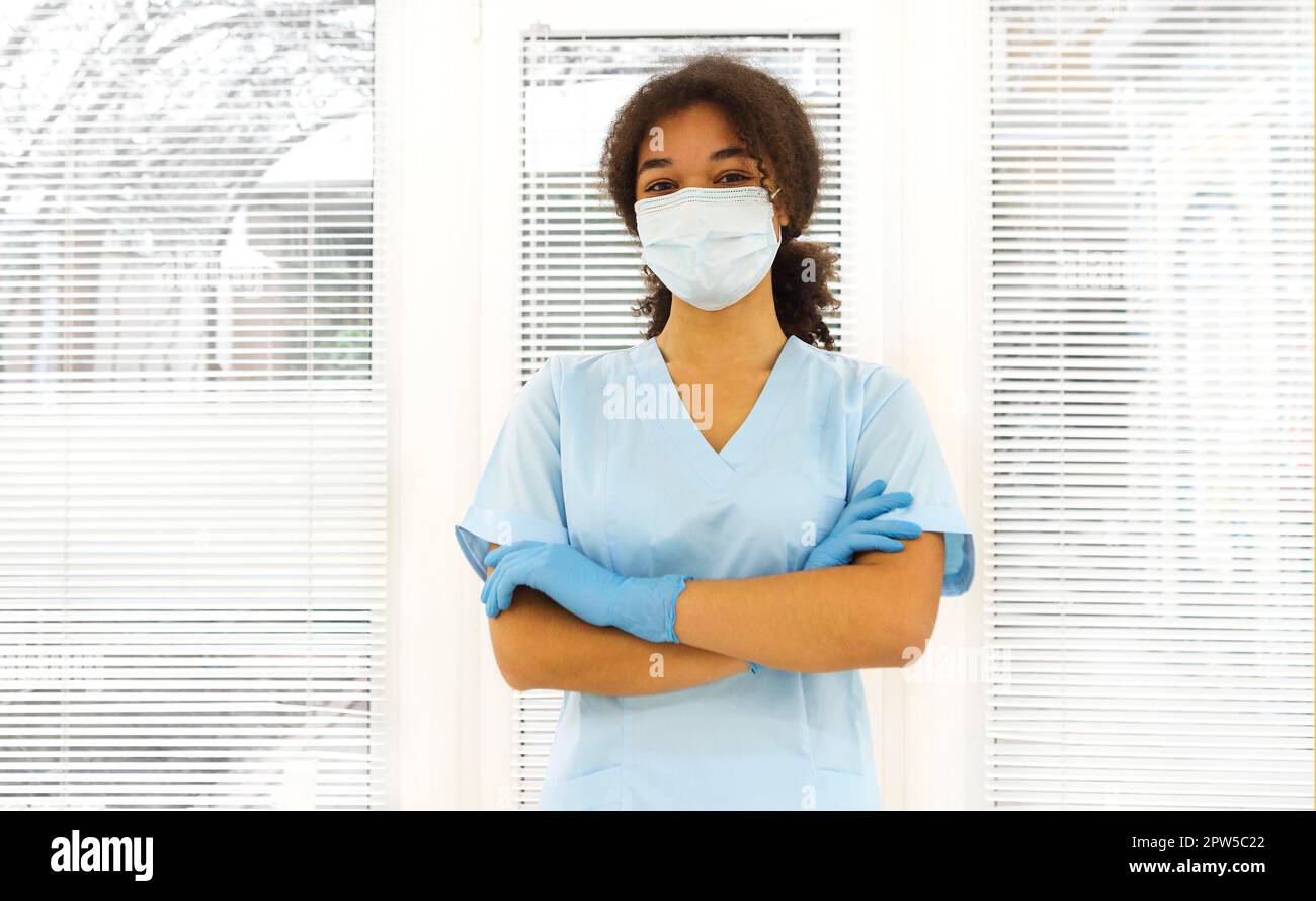 Junge müde überarbeitete afroamerikanische medizinische Arbeiter tragen Gesichtsschutzmaske, die mit frustrierten Ausdruck auf die Kamera schaut. Gesundheitswesen Stockfoto
