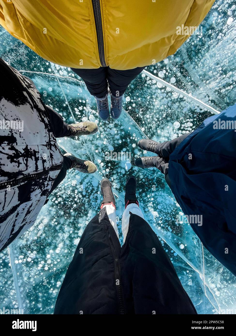 Zerbrechliches, dünnes, brüchiges Eis unter dem Fuß. Männer und Frauen Füße auf Eis, Leute tragen Winterschuhe auf Eis von Baikal, Russland. Risse auf Eishintergrund. Eis Stockfoto