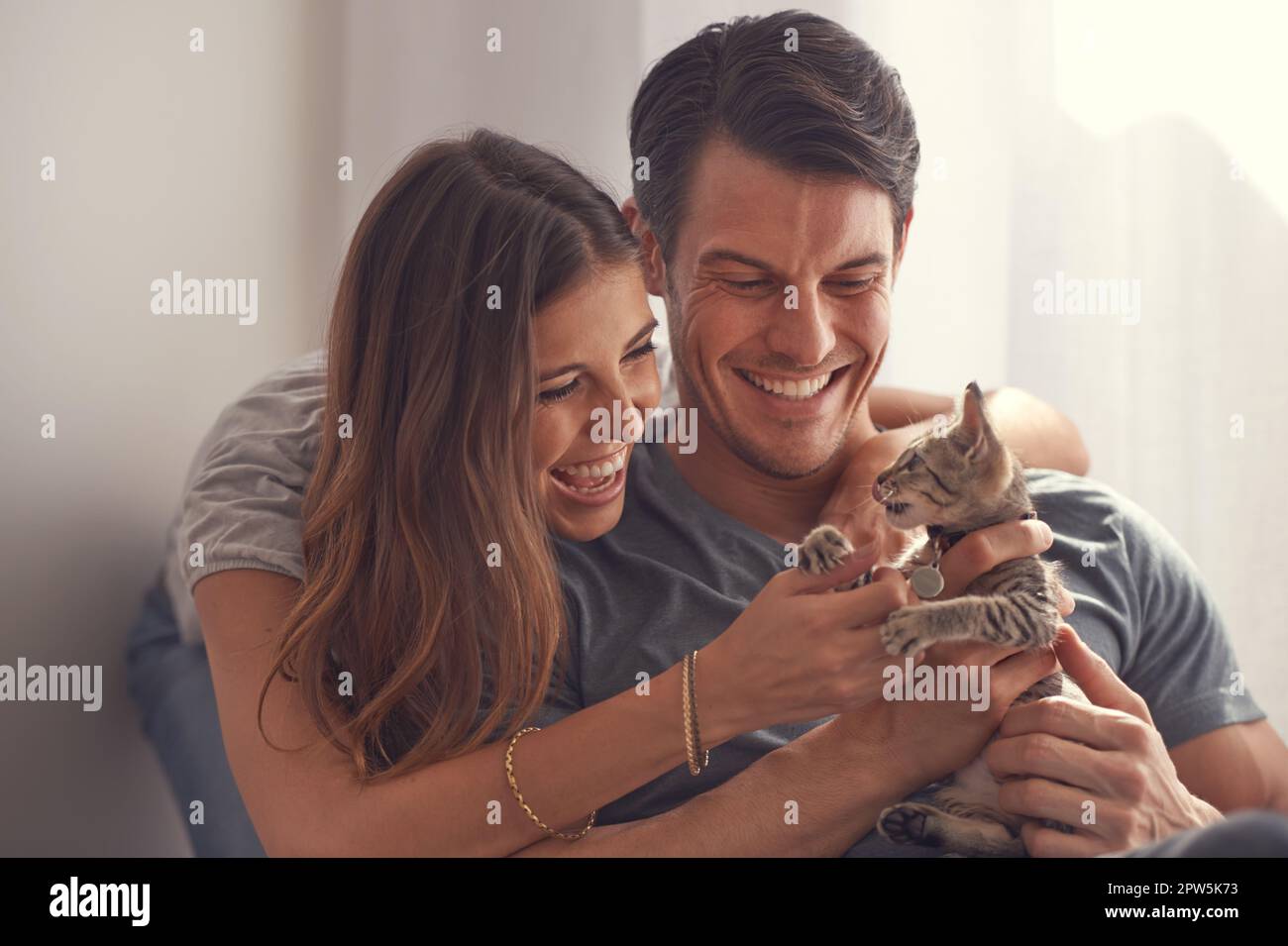 Kuscheln und Süße. Ein liebevolles junges Paar, das mit seinem Kätzchen sitzt Stockfoto