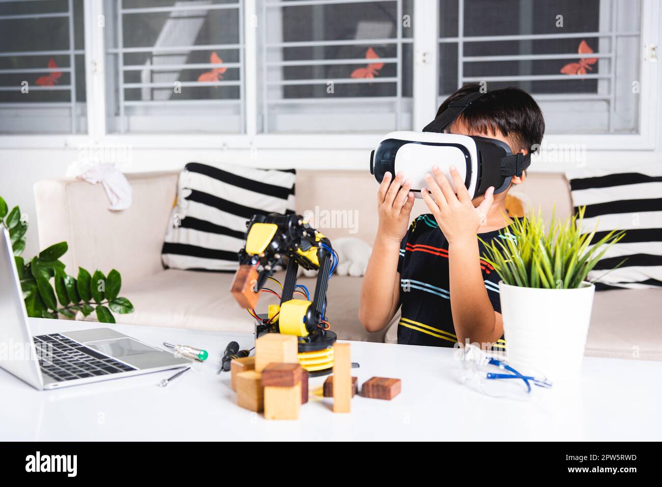 Virtual Reality Simulator. Asiatische Kind Junge mit VR-Brille auf Roboterarm in der Werkstatt, Kind lernen Programmierer steuern Roboterarm mit Sensoren zu holen Stockfoto