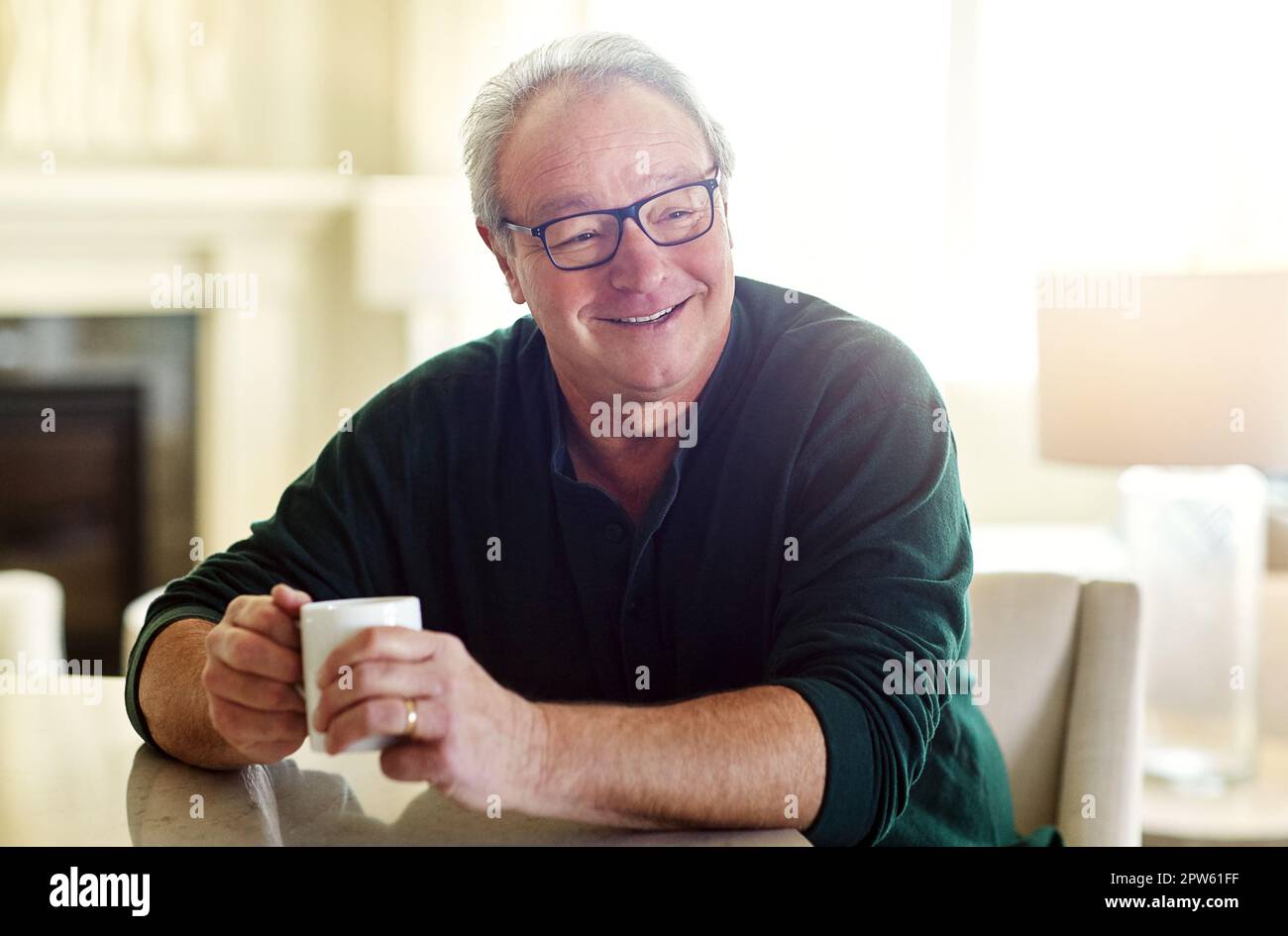 Es geht nichts über eine Tasse Kaffee am Morgen. Ein älterer Mann, der sich zu Hause entspannt. Stockfoto