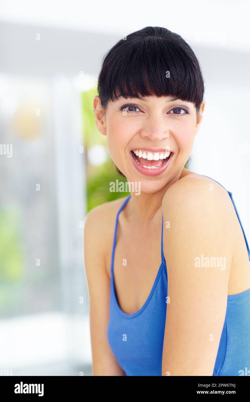 Sie hat eine sonnige Einstellung. Eine reizende junge Frau, die lacht und ein großes Lächeln schenkt Stockfoto