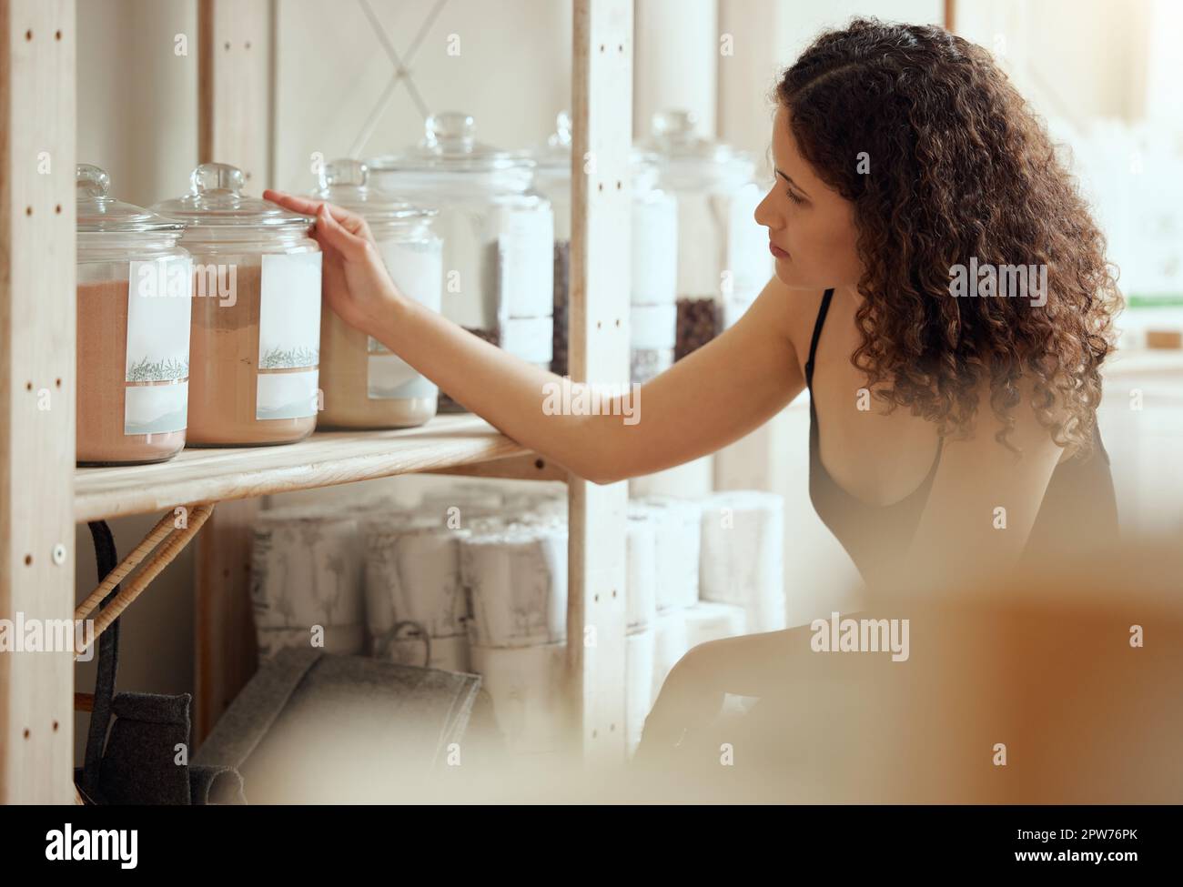 Keine Abfälle beim Einkaufen oder bei der Auswahl von Bio- und veganen Produkten oder Gewürzen in einem Regal eines Ladens. Eine junge Kundin oder Konsument, die Gewürze im Glas kauft Stockfoto