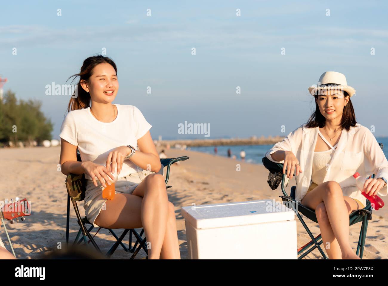 Glückliche Freunde mit Getränken im Camp und lachen zusammen in Urlaub am Sandstrand in der Nähe Camping Zelt Urlaubszeit bei Sonnenuntergang, Junge asiatische Gruppe Frau A Stockfoto