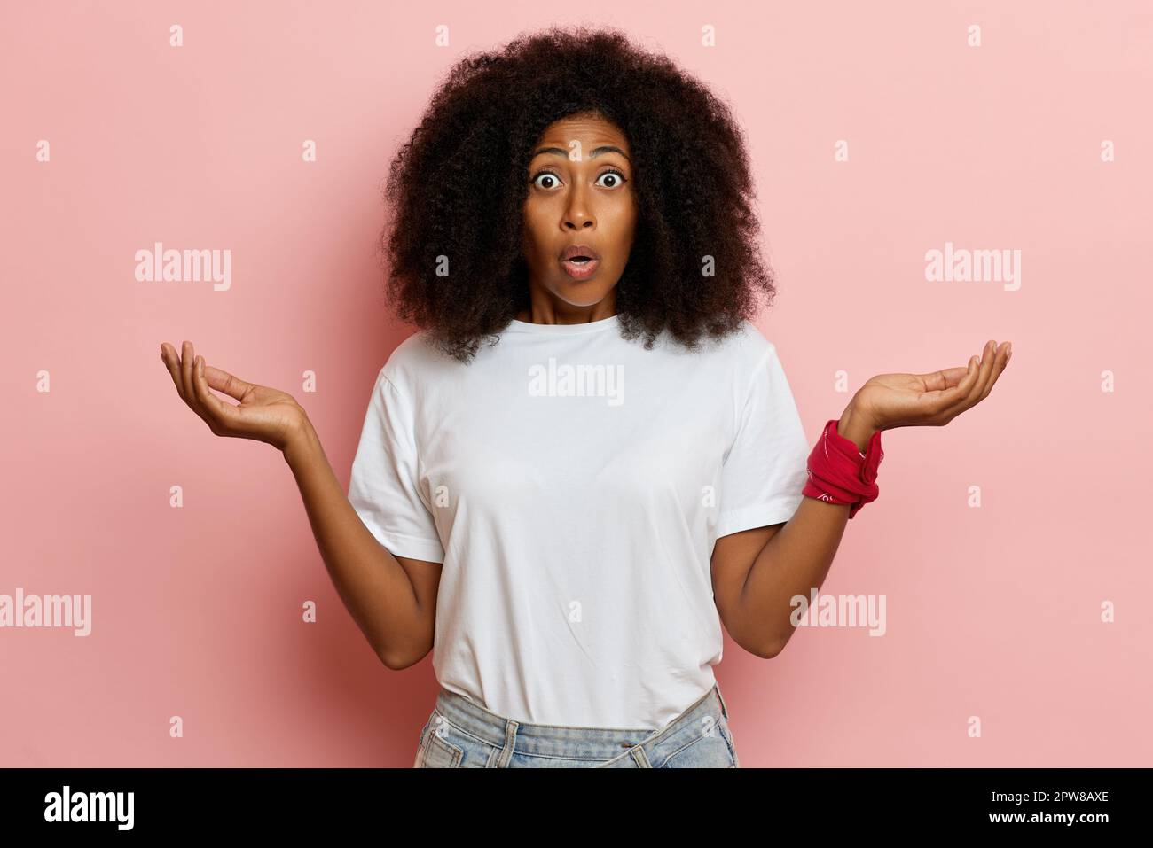 Eine junge afroamerikanische Frau, die mit weit geöffneten Augen in die Kamera schaut, die Hände in eine alberne Überraschung steckt. Hochwertiges Foto Stockfoto