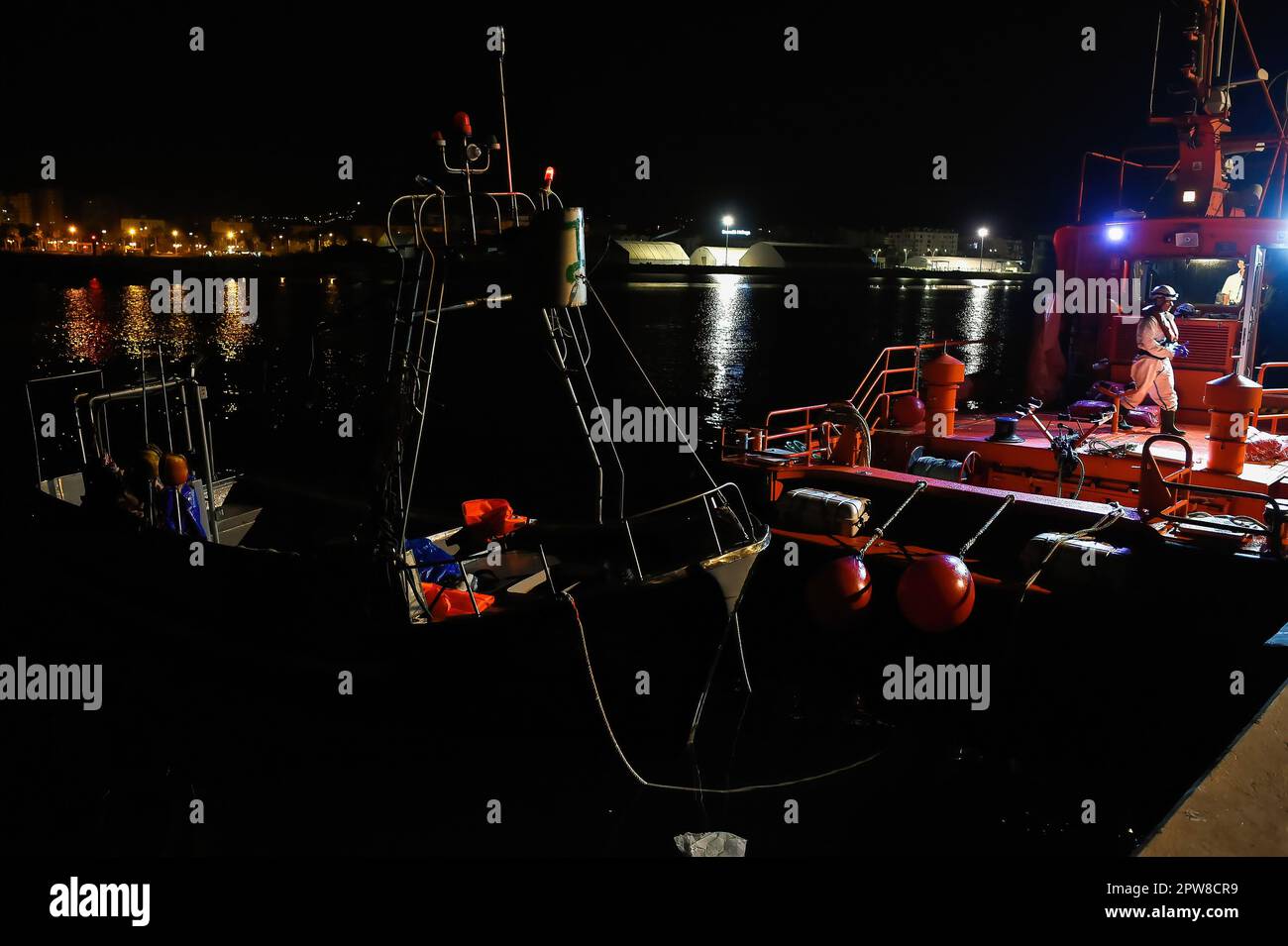 Ein kleines Boot (L), das von Migranten, die im Mittelmeer gerettet wurden, als Beiboot genutzt wird, ist im Hafen von Malaga zu sehen. Salvamento Maritimo rettete ein Schlauchboot, das mit Dutzenden Migranten an Bord die spanische Küste erreichen wollte, und überführte sie in den Hafen von Malaga, wo sie vom spanischen Roten Kreuz unterstützt wurden. Eine intensive Grenzpatrouille durch die marokkanischen Behörden hat zu einem drastischen Rückgang der Zahl der Migranten geführt, die versuchen, die spanischen Küsten über die Alboran-Meerestrecke zu erreichen. Die Ankunft von Migranten an den Küsten der Kanarischen Inseln (eine der gefährlichsten Migrationsrouten) hat zugenommen Stockfoto