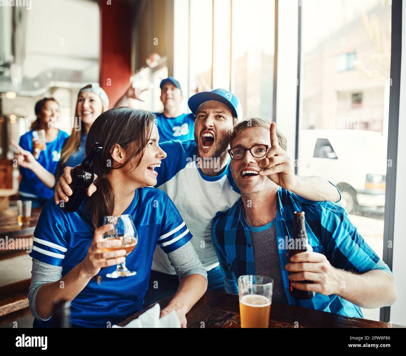 Es verwandelt sich in ein episches Spiel. Eine Gruppe von Freunden, die Bier trinken, während sie sich ein Sportspiel in einer Bar anschauen. Stockfoto