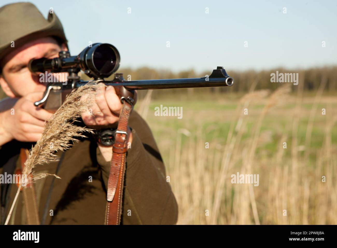 Jagd, Waffe und Mann auf einer Afrika-Safari im Gras, um Tiere im Urlaub zu erschießen. Waffe, Scharfschütze und männlicher Mensch zielen auf Wildtiere in der Natur Stockfoto