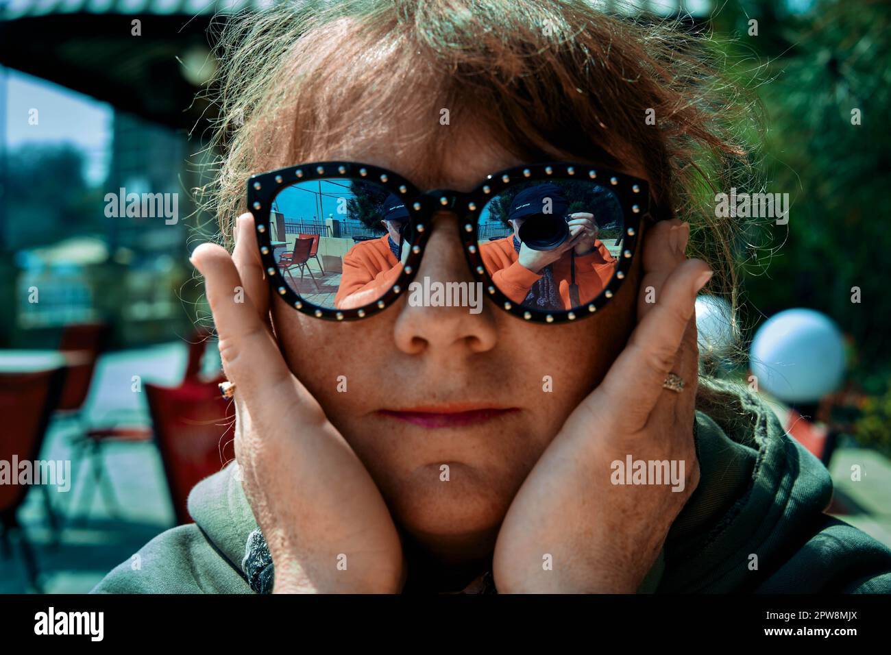 Erwachsene, reife Frau mit Sonnenbrille und ein Fotograf, der sich in Odessa Ukraine am Seeufer in ihnen spiegelt Stockfoto