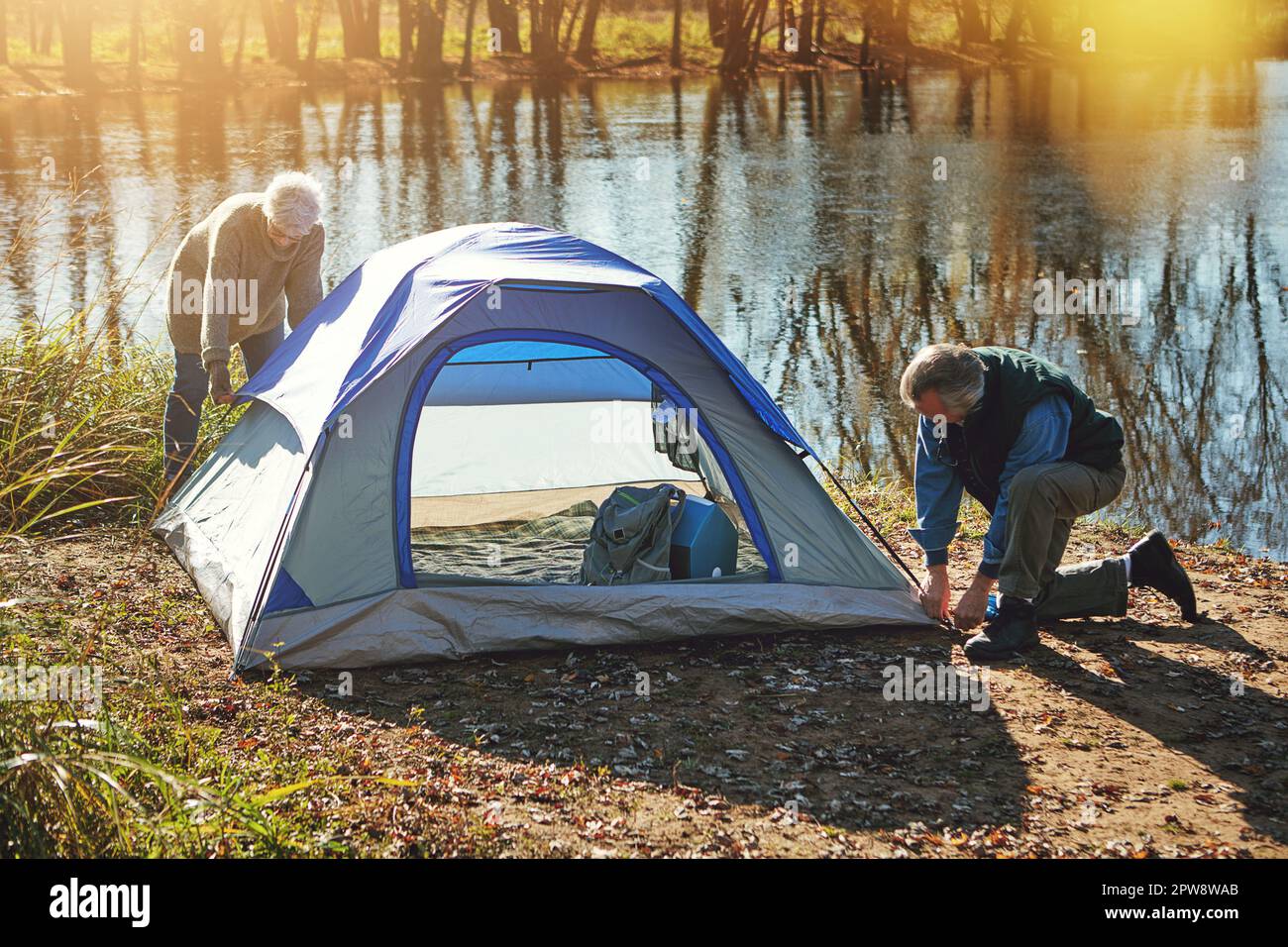 Es ist der perfekte Ort, um ein Camp aufzubauen. Ein Seniorenpaar, das ein Zelt aufbaut, während es in der Wildnis zeltet. Stockfoto