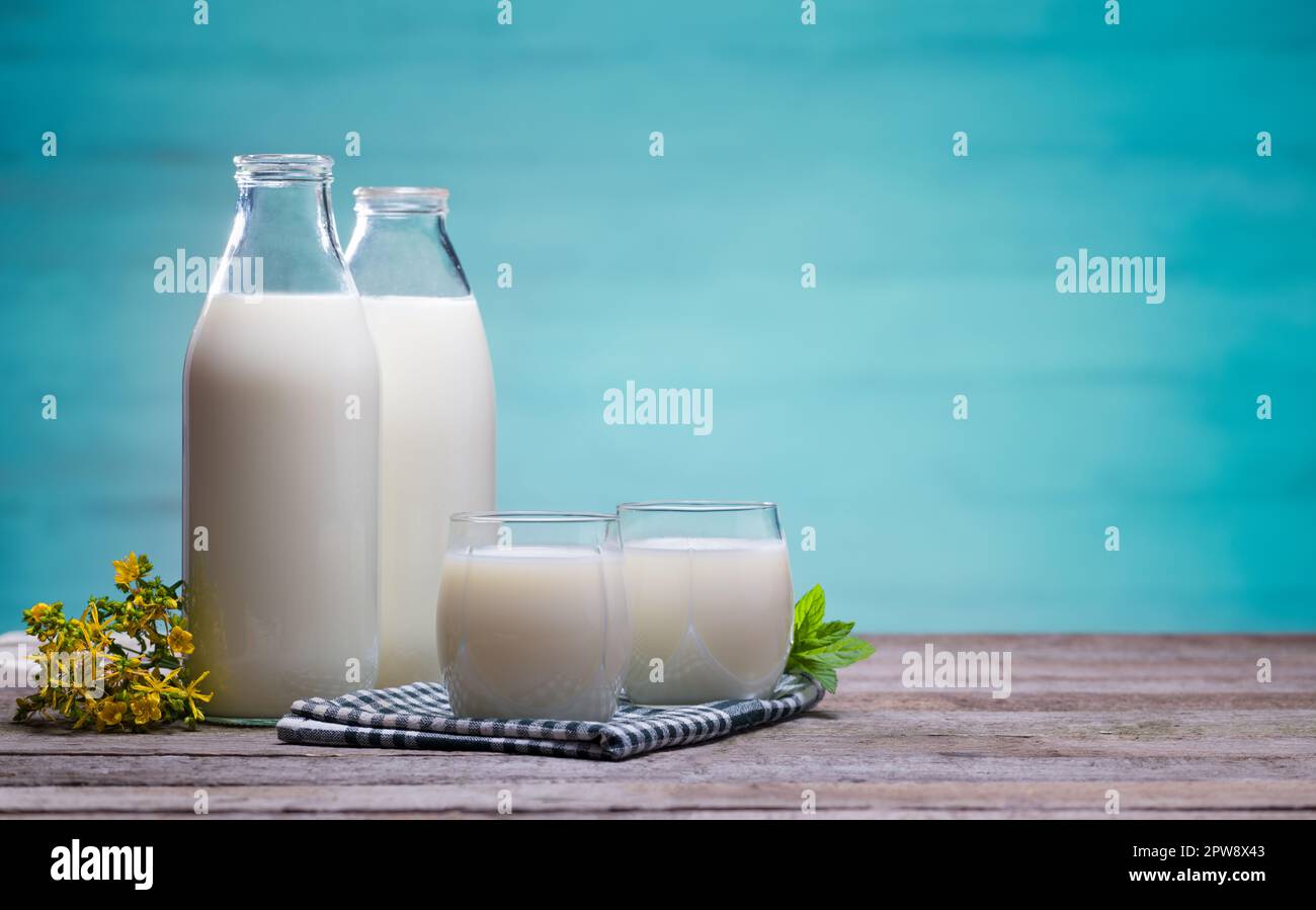 Milchflaschen und Gläser voller Milch auf einem Holztisch. Frischmilchkonzept. Stockfoto