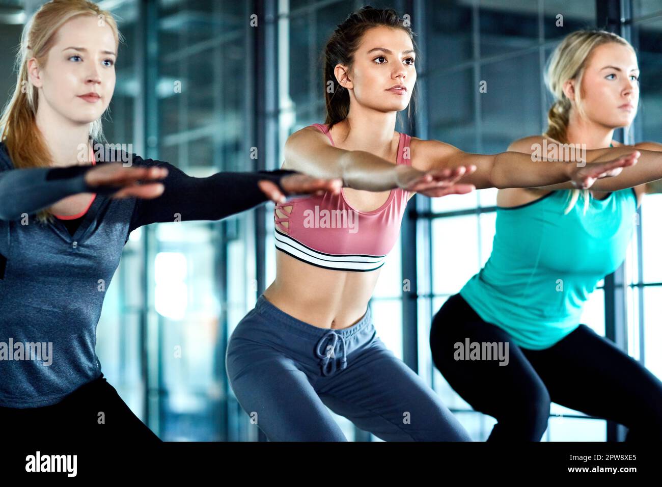 Sie werden zusammen fitter. Drei attraktive junge Frauen trainieren zusammen im Fitnessstudio. Stockfoto