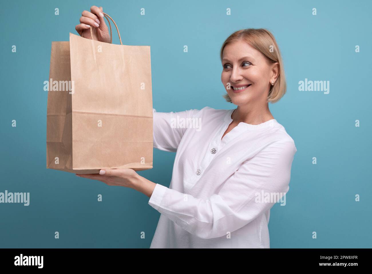 Zufriedene Frau mittleren Alters mit brauner Handwerkstasche Stockfoto
