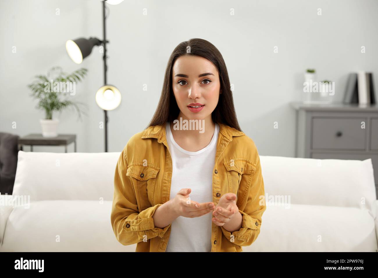 Junge Frau, die ein Webinar im Zimmer zu Hause durchführt Stockfoto