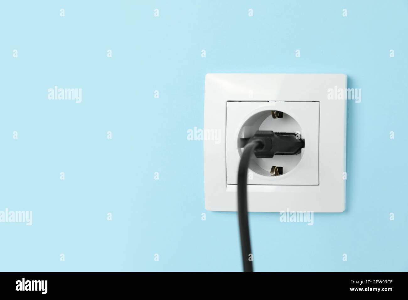 Steckdose mit eingestecktem Stecker an hellblauer Wand, Platz für Text.  Stromversorgung Stockfotografie - Alamy