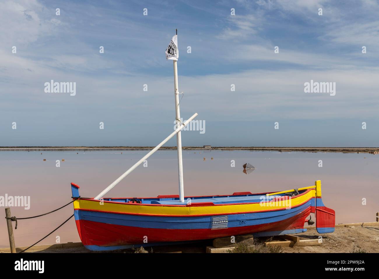 Farbenfrohes Segelboot fährt vor dem rosa Meer in Le Salin de Gruissan im Departement Aude Stockfoto