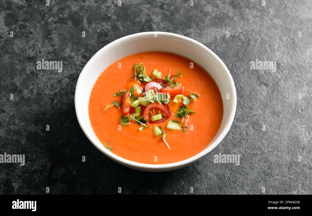 Gazpacho-Suppe in Schüssel auf dunklem Steinhintergrund. Kalte Tomatensuppe. Nahaufnahme Stockfoto