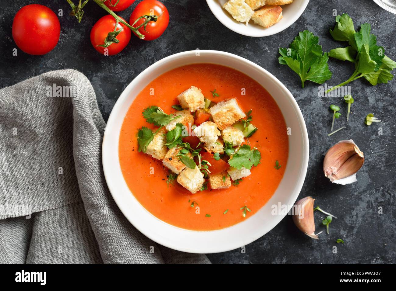 Tomaten-Gazpacho-Suppe in Schüssel mit dunklem Steinhintergrund. Gesundes Lebensmittelkonzept. Draufsicht, flach liegend Stockfoto