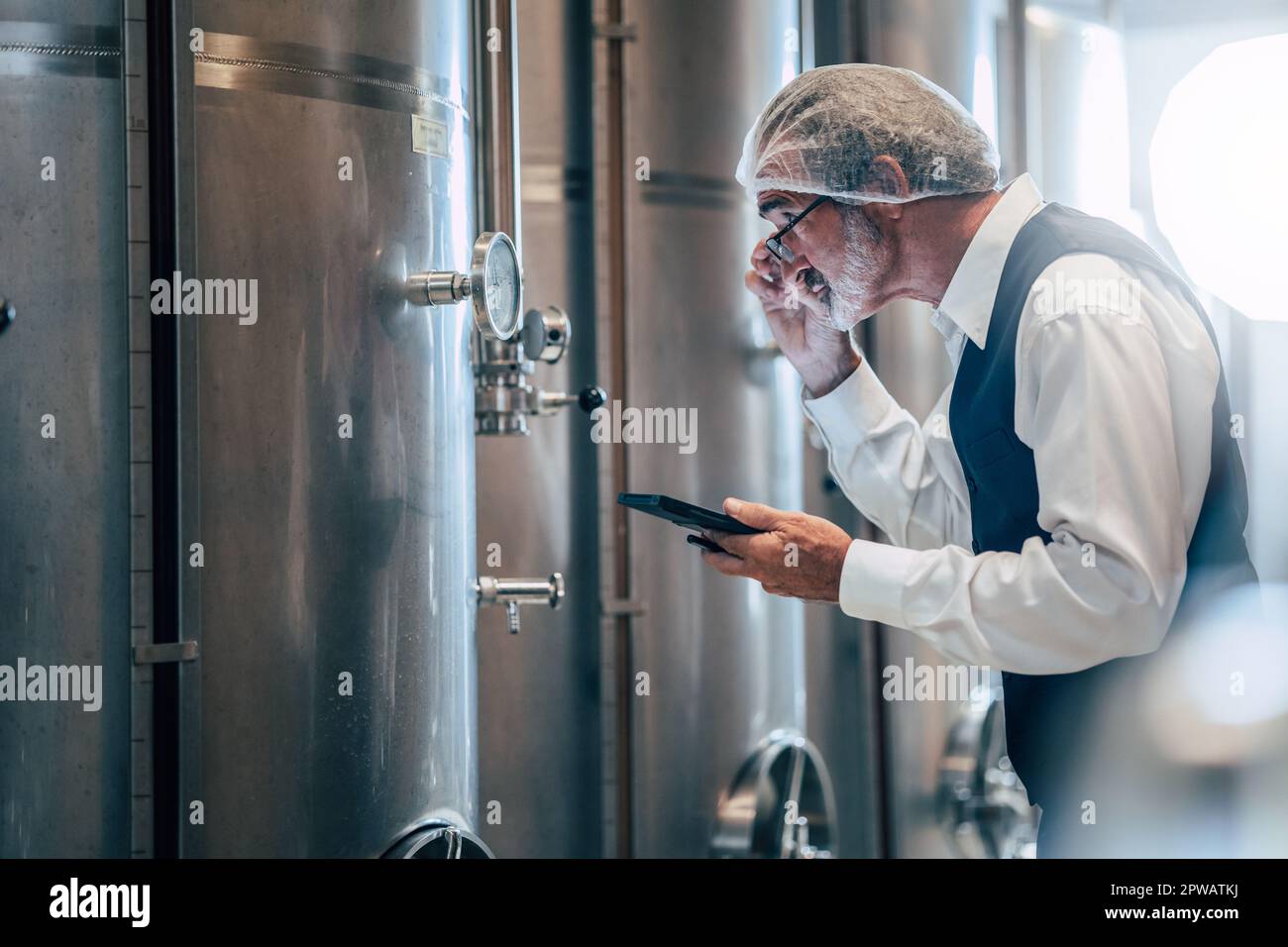 Winzer, der in einer modernen großen Weinfabrik arbeitet, überwacht Qualität und Gärung der Spirituosenindustrie Stockfoto