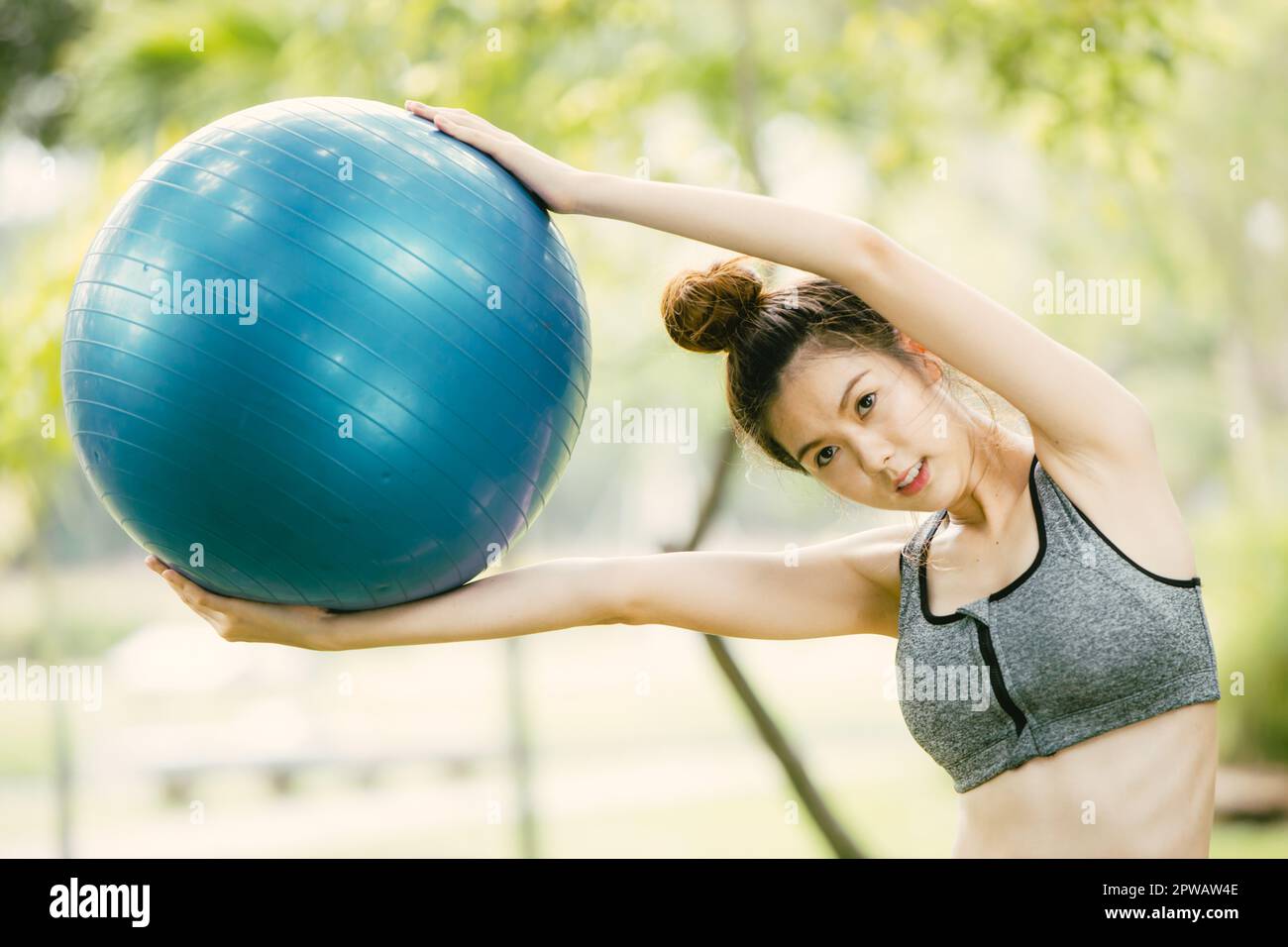 Schöne asiatische glückliche Frau Spielen Sie Spaß mit fit Ball Training im Park Outdoor schlanke und gesunde Mädchen Workout Aktivität. Stockfoto