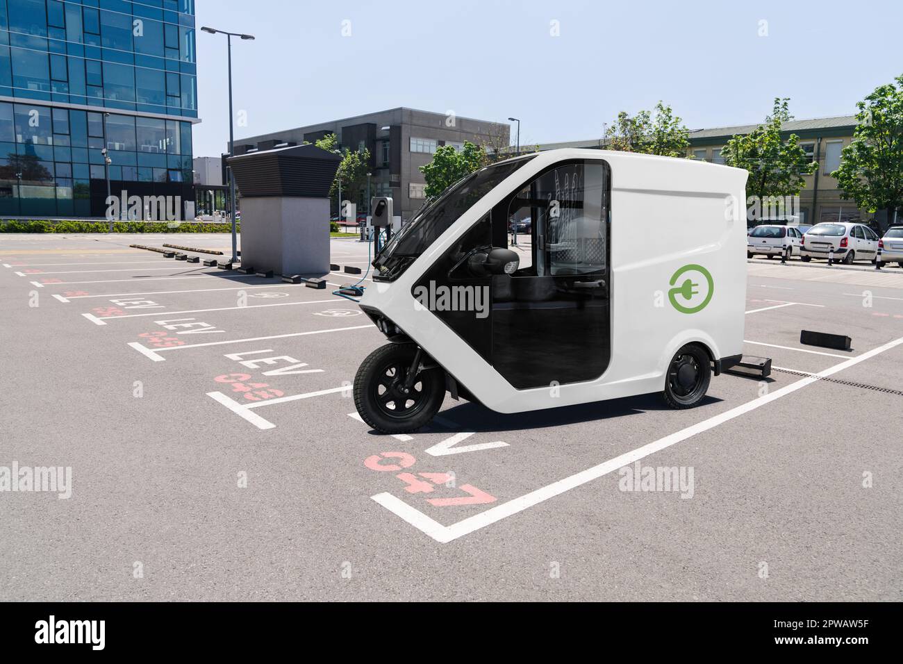 Elektrischer Dreirad-Roller mit Ladestation auf einem Parkplatz für leichte LEV-Elektrofahrzeuge. Stockfoto