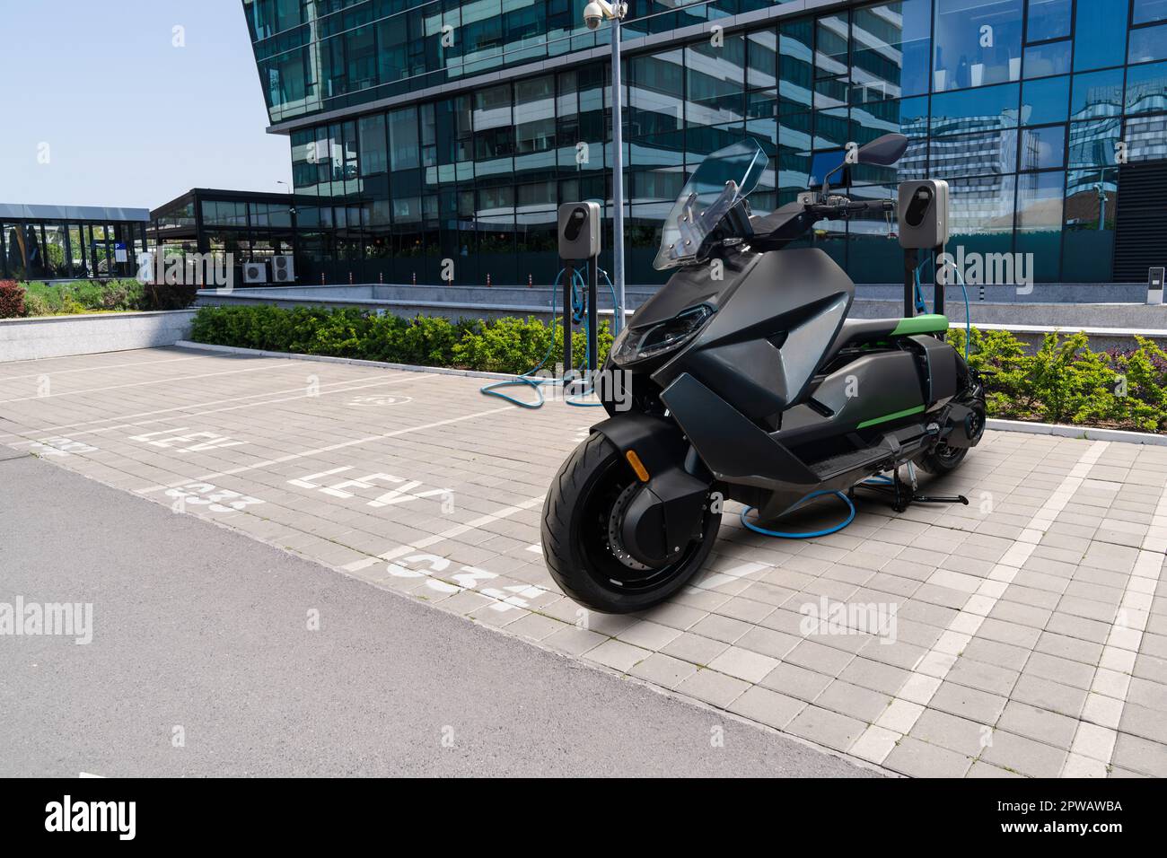 Elektrischer Roller mit Ladestation auf einem Parkplatz für leichte LEV-Elektrofahrzeuge. Stockfoto