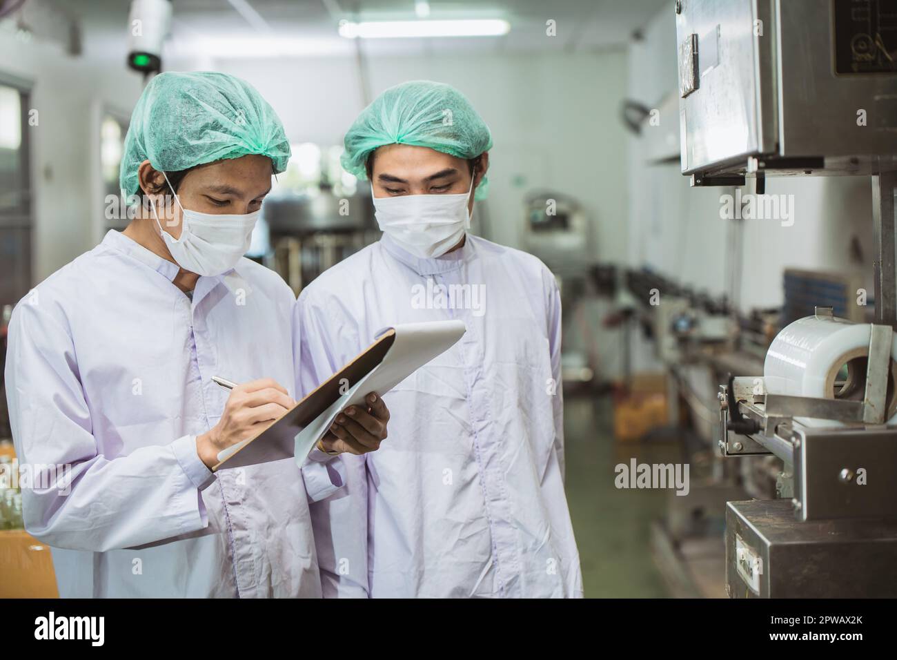 Männliche Arbeiter, die in der Getränkefabrik mit Hygiene und Sauberkeit zusammenarbeiten. Prozess zur Prüfung der Produktqualität durch den Mitarbeiter. Stockfoto