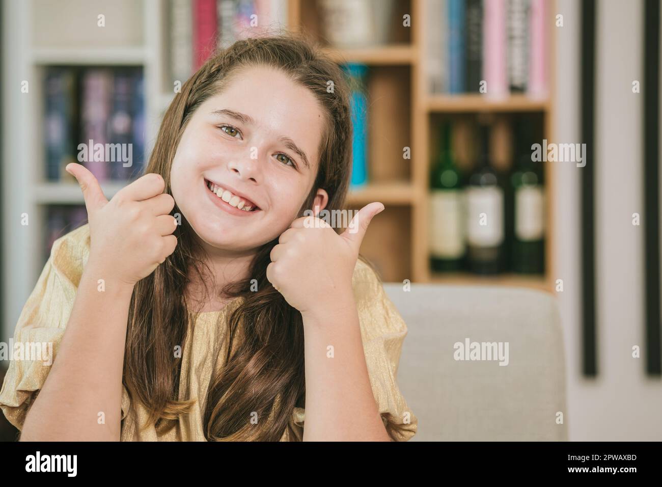 Süßes Kind kleines Mädchen Kaukasisches braunes Haar glücklich lächelnd zwei Daumen hoch wie Lesen und Bildung in der Schule Stockfoto