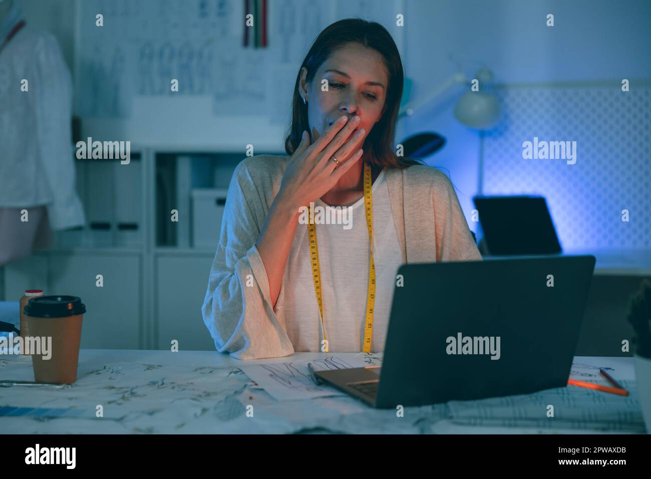 Kleiderdesignerin, die über Nacht fleißig im Schneiderstudio arbeitet Stockfoto