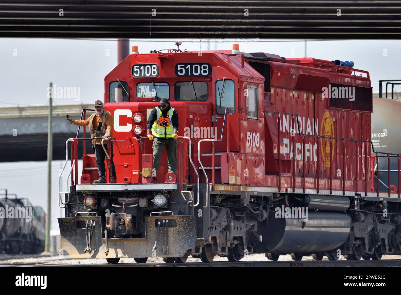 Franklin Park, Illinois, USA. Mit zwei Besatzungsmitgliedern, die auf dem vorderen Bahnsteig einer Lokomotive sitzen, wechselt ein Güterzug die Autos am Rande eines Gartens. Stockfoto