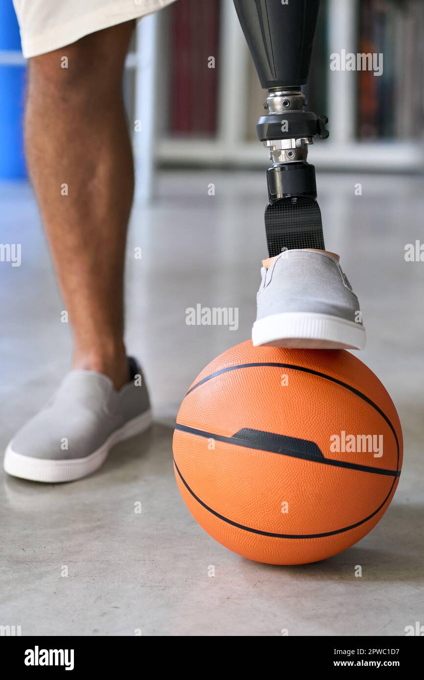 Amputierter Mann mit Beinprothesen in Pose mit Basketballball. Stockfoto