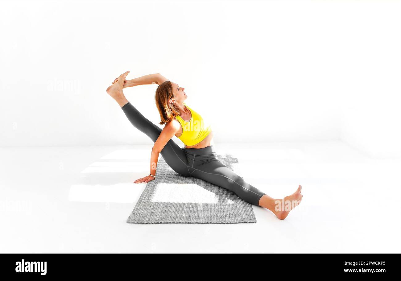 Seitenansicht der ruhigen Frau in Sportkleidung Yoga üben während Balancieren auf den Armen auf der Matte und wegschauen Stockfoto