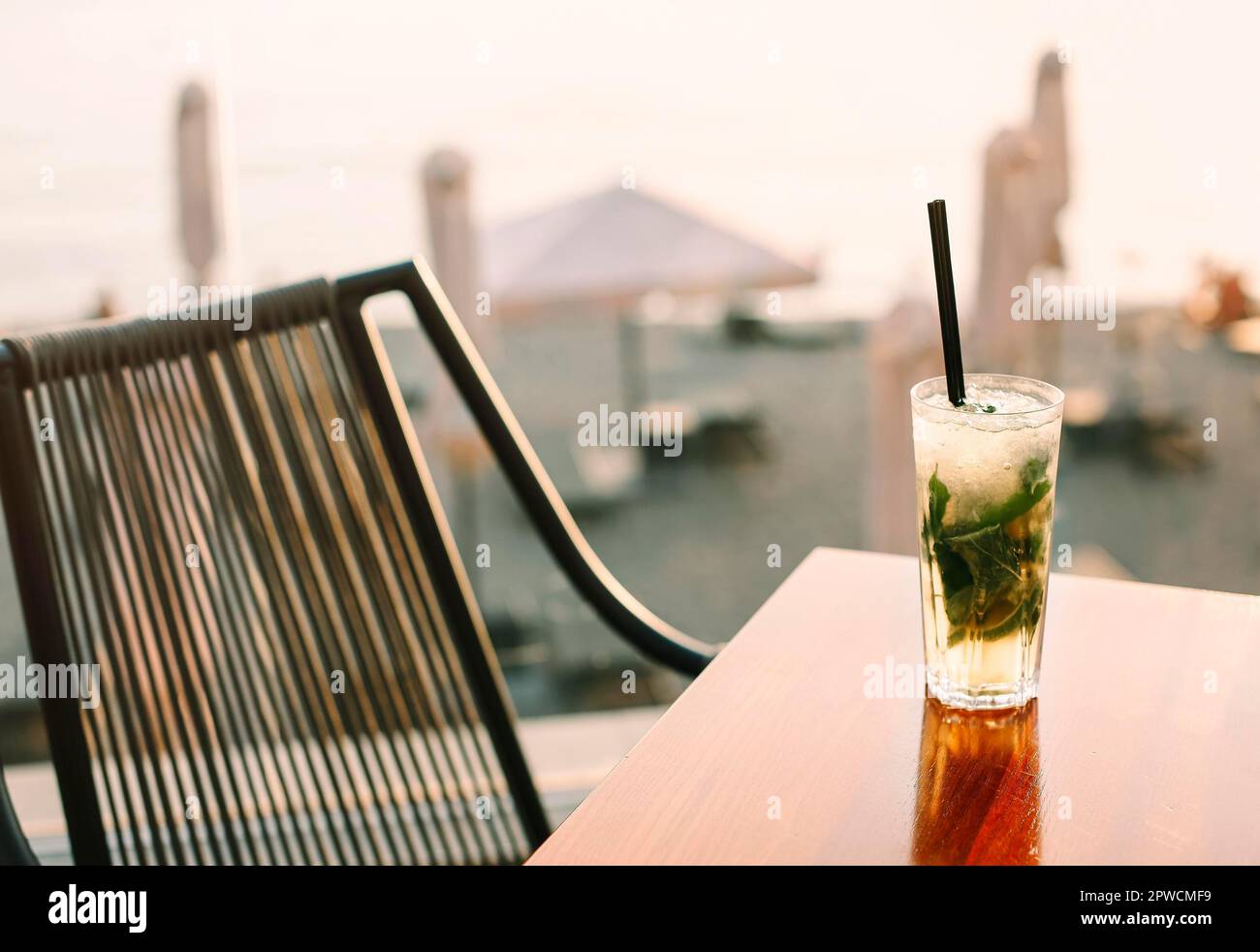 Am Sommertag werden in der Bar ein großer Glasswinkel mit süßen kalten Cocktails und Trinkhalmen auf den Tisch gelegt Stockfoto