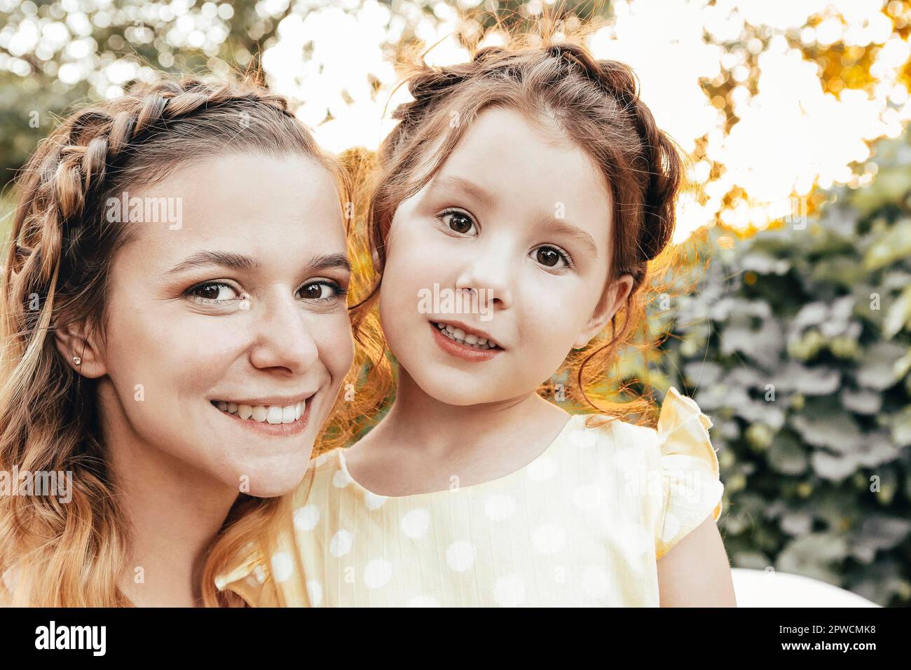 Nettes kleines Rotschopf Mädchen und glückliche junge Mutter mit ähnlichen geflochtenen Frisur umarmt zusammen Stockfoto